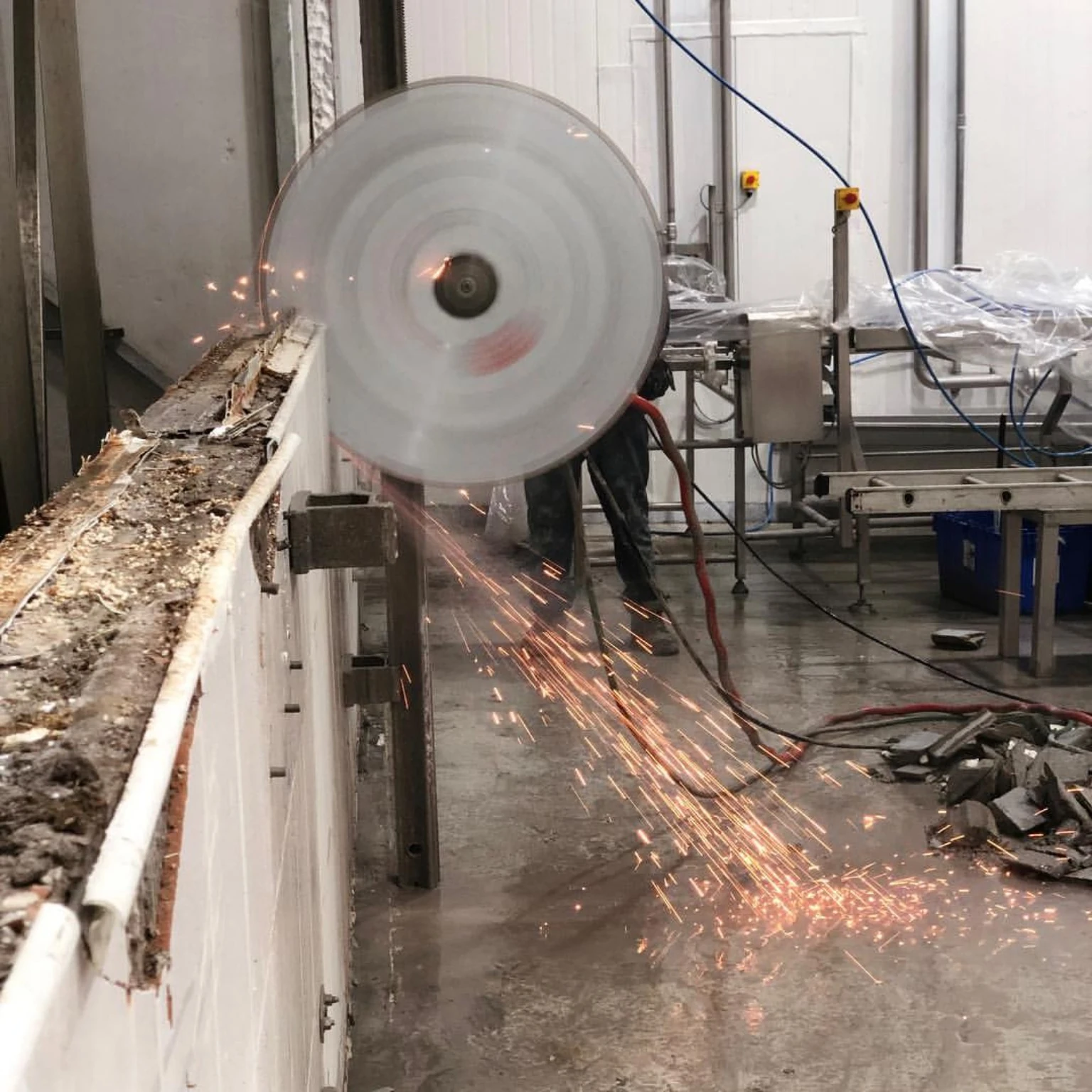 Operario trabajando con un equipo de corte con disco diamantado sobre hormigón.