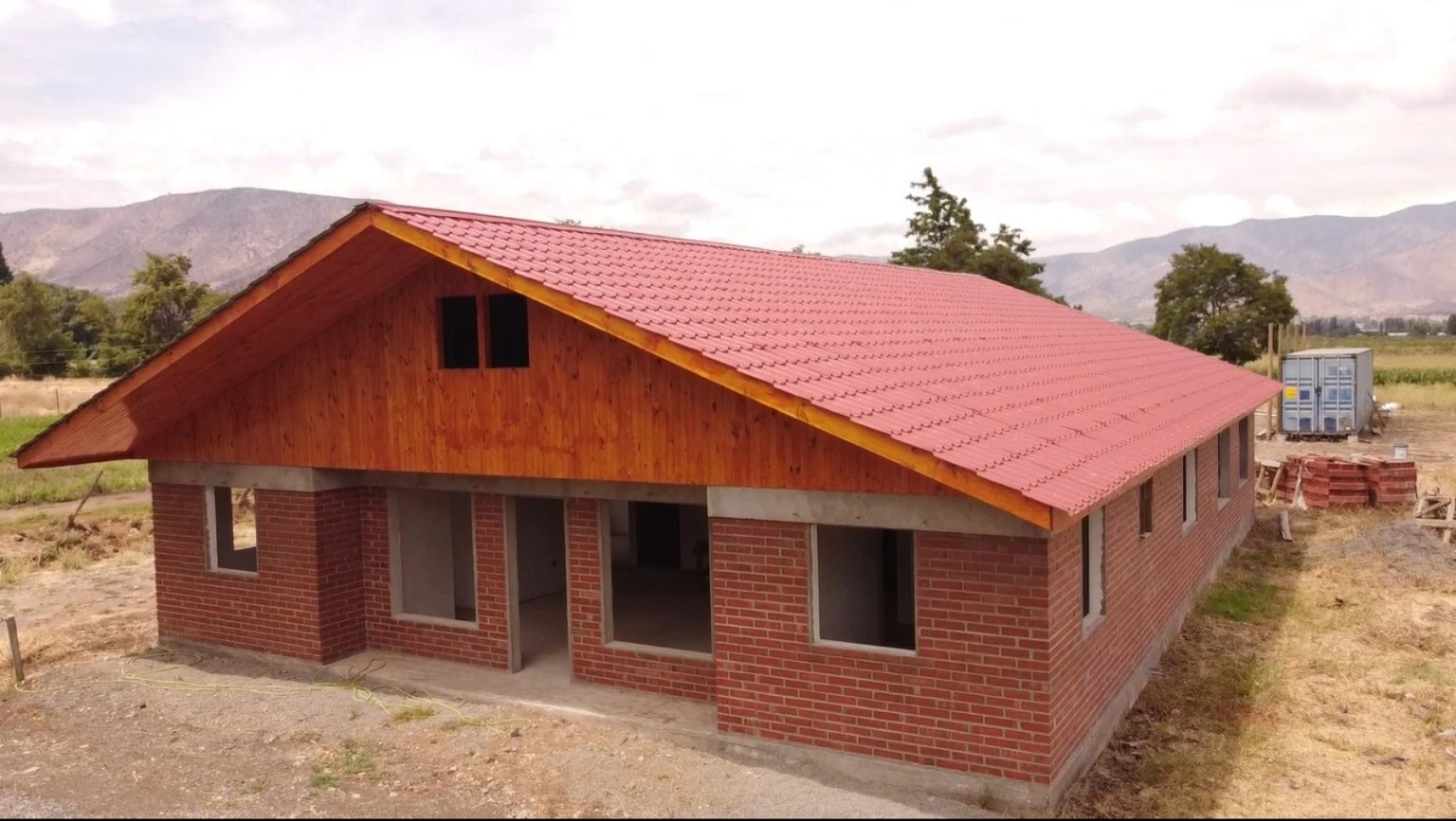 Vista de una vivienda de albañilería con cubierta instalada y vanos sin ventanas durante su construcción.